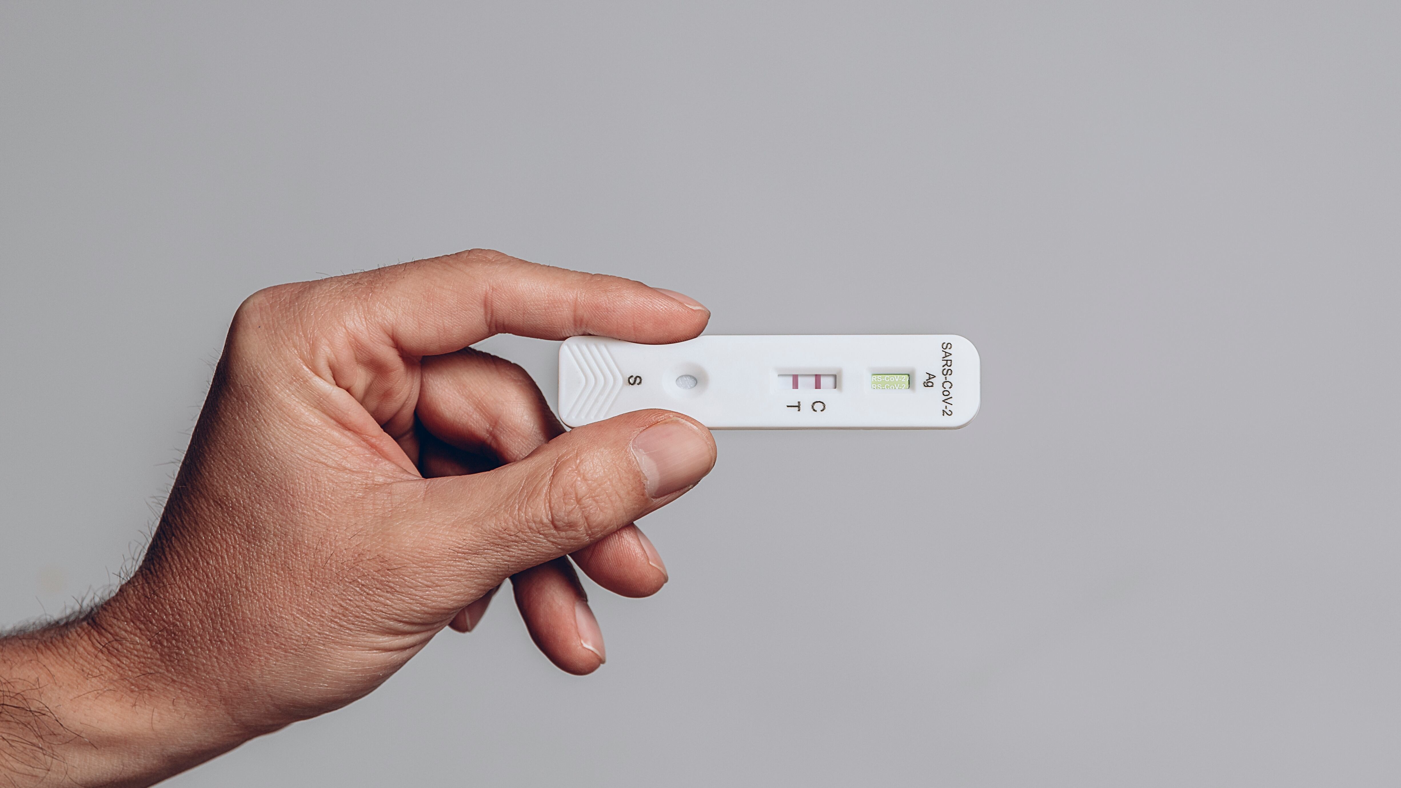 hand holds covid antigen test showing positive result on gray background in study shot