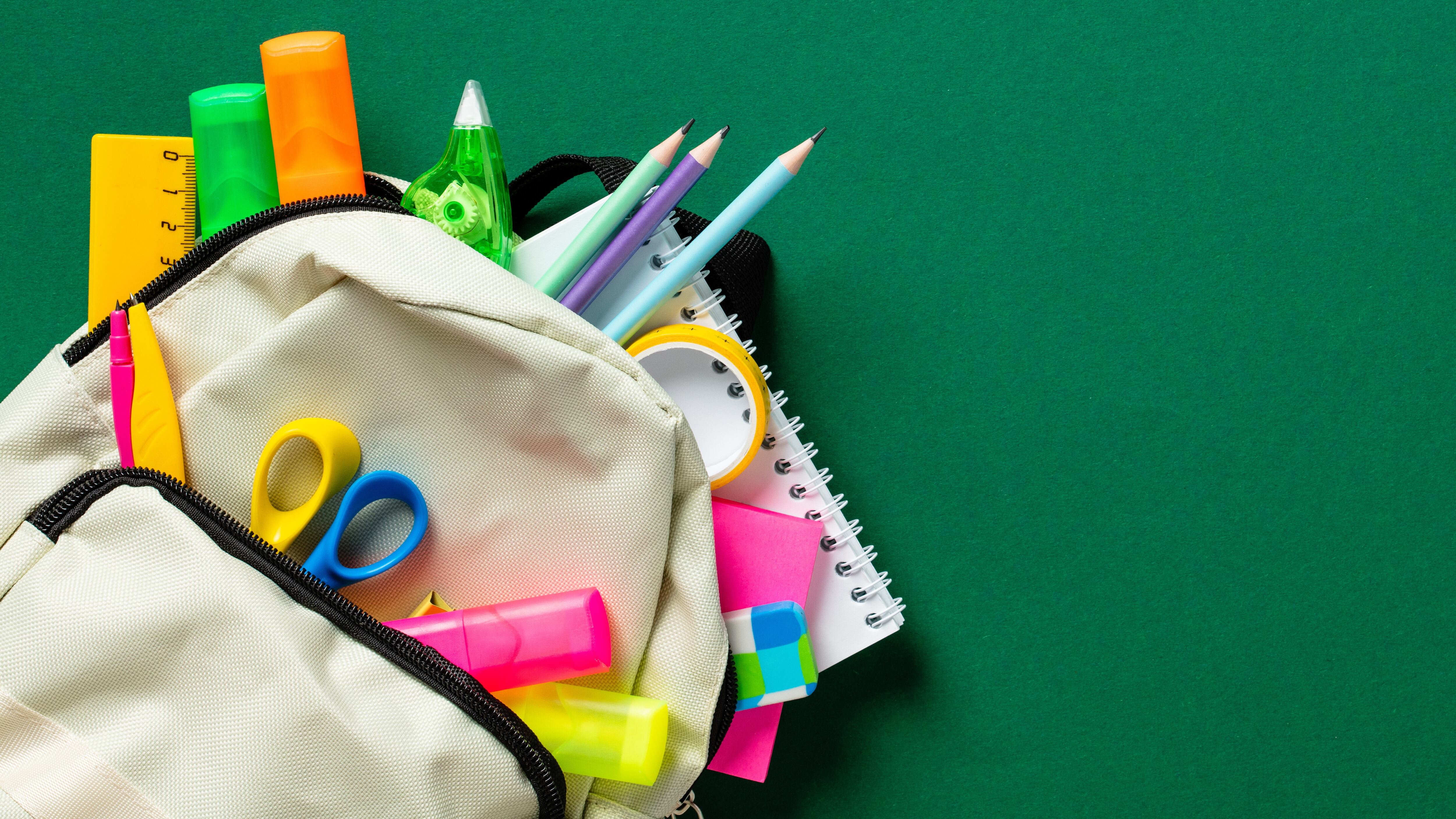 Backpack with colorful school supplies on green background. Back to school sale banner design.